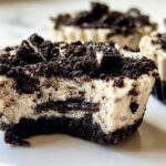 Close-up of a Healthy No-Bake Oreo Cheesecake Bite with a bite taken out, showing layers of cream cheese and crushed Oreos.