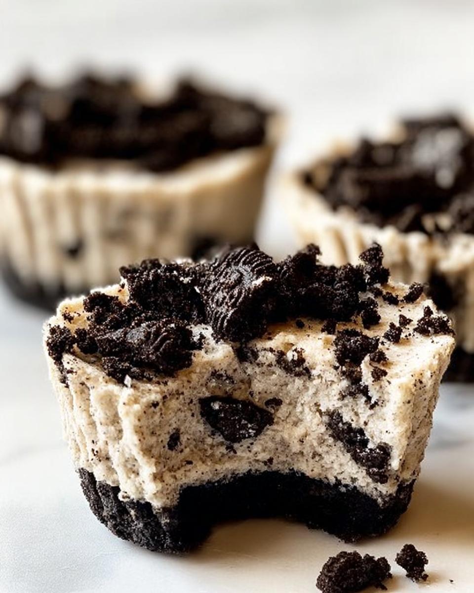 A close-up of a bite taken out of a Healthy No-Bake Oreo Cheesecake Bite, showing the creamy filling and Oreo cookie crust.