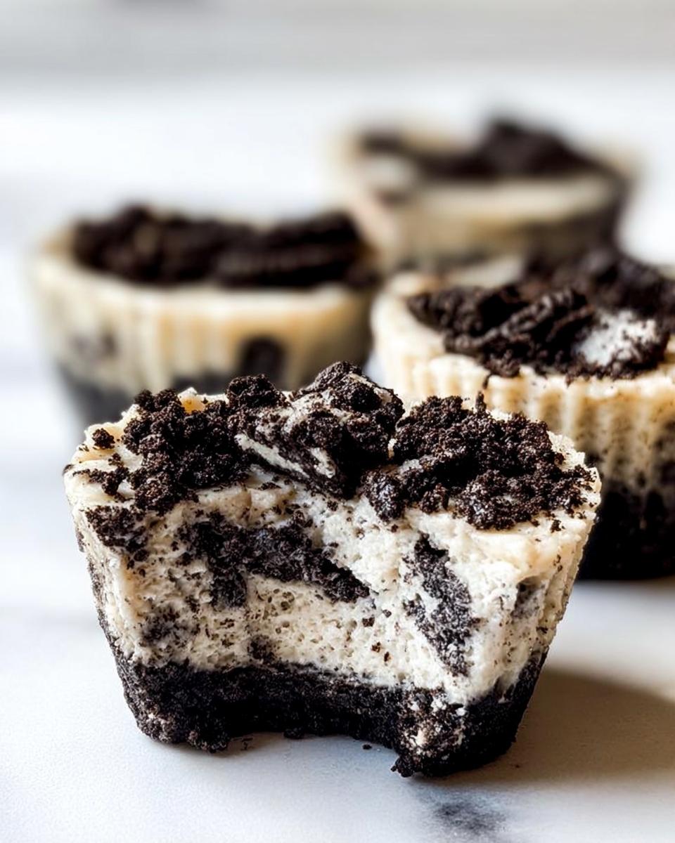 A close-up of a Healthy No-Bake Oreo Cheesecake Bite with a bite taken out, showing the creamy filling and crushed Oreo topping.