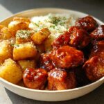 A bowl filled with Honey BBQ Chicken and Garlic Parmesan Potatoes, topped with shredded cheese and parsley.