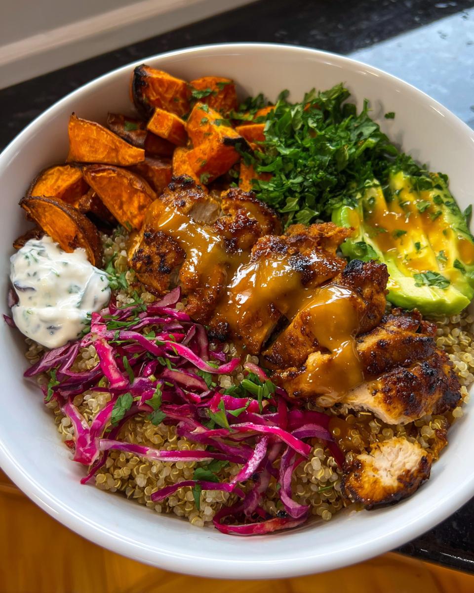 A vibrant Hot Honey Chicken Bowl Recipe featuring grilled chicken, quinoa, roasted sweet potatoes, avocado, and a creamy sauce.