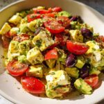 A close-up of Simple & Zesty Mediterranean Avocado Egg Salad with cherry tomatoes, olives, and feta cheese.