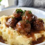 A bowl of Salisbury Steak Meatballs with Garlic Herb Mashed Potatoes, topped with fresh parsley.