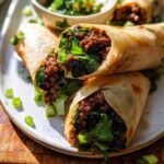Close-up of three Thai Basil Beef Rolls on a plate, filled with savory ground beef and fresh herbs.