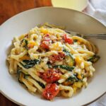 A bowl of delicious Tomato Zucchini Pasta, topped with grated Parmesan cheese and fresh herbs.