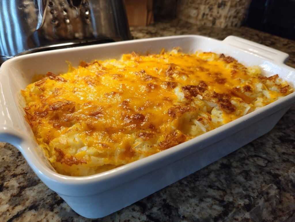 A golden brown, cheesy hash brown casserole baked in a white dish, perfect for breakfast ideas.