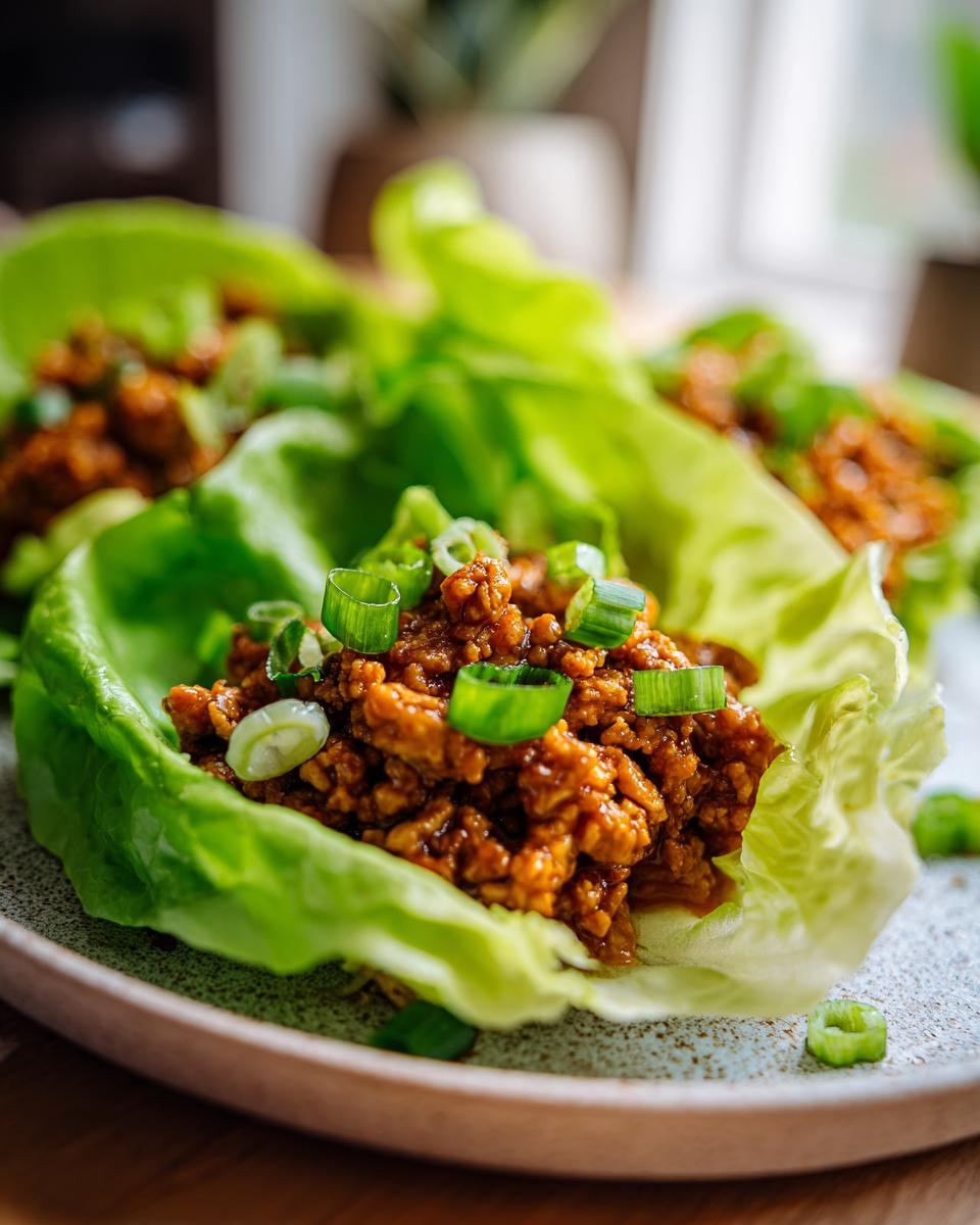 Close-up of fresh chicken lettuce wraps, a healthy lunch idea, topped with chopped green onions.