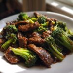 A close-up of a plate filled with tender slices of Chinese Beef and Broccoli in a savory sauce.