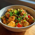A bowl of Creamy Cajun Chicken & Rice Bowls topped with chopped green onions and red bell peppers.