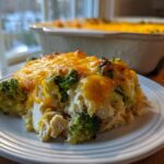 A serving of creamy low carb chicken casserole with broccoli and melted cheese on a white plate.