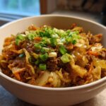 A close-up of a white bowl filled with a savory Egg Roll in a Bowl, topped with fresh green onions.