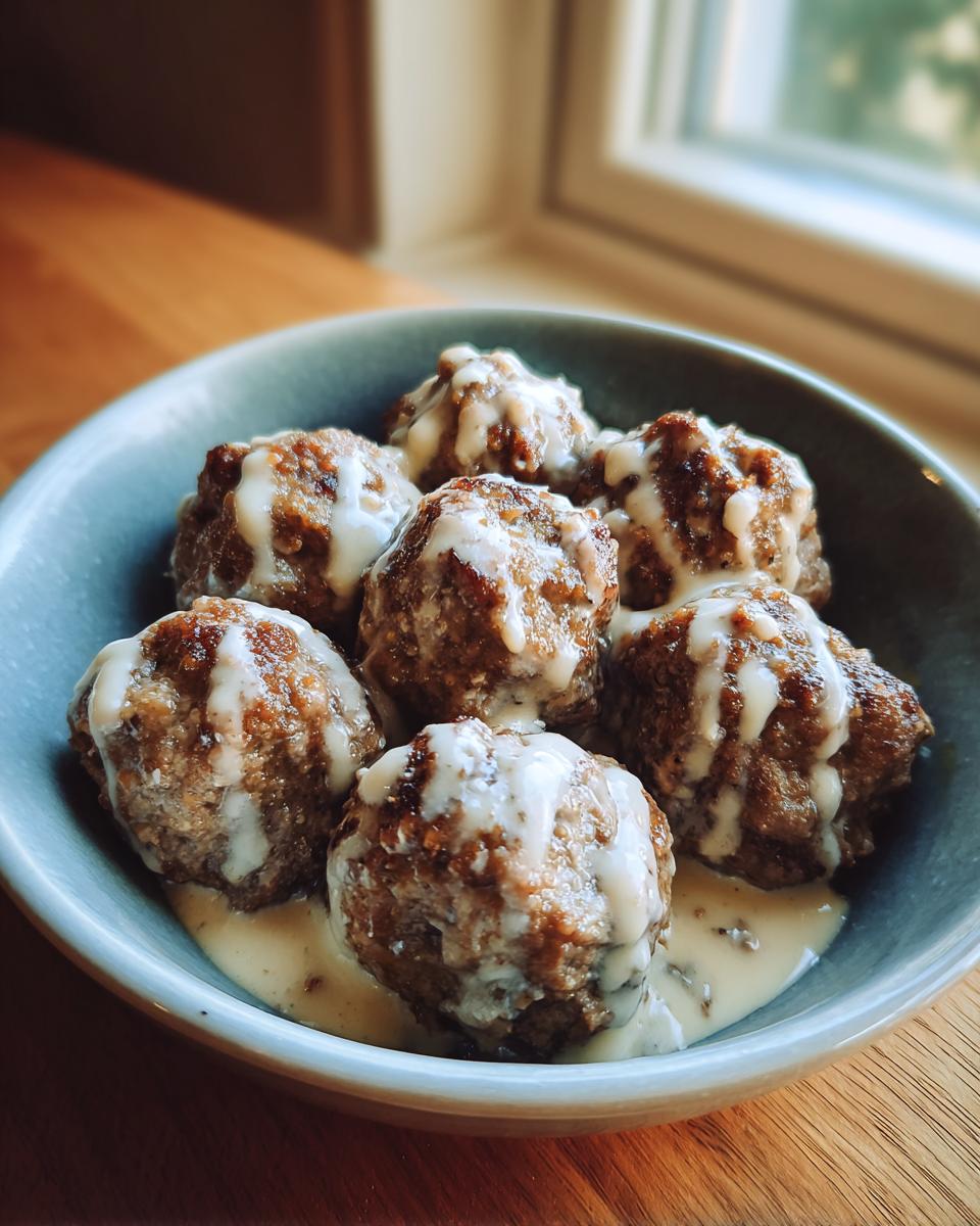 A bowl of delicious Swedish meatballs drizzled with a creamy sauce, perfect for ground beef recipes.