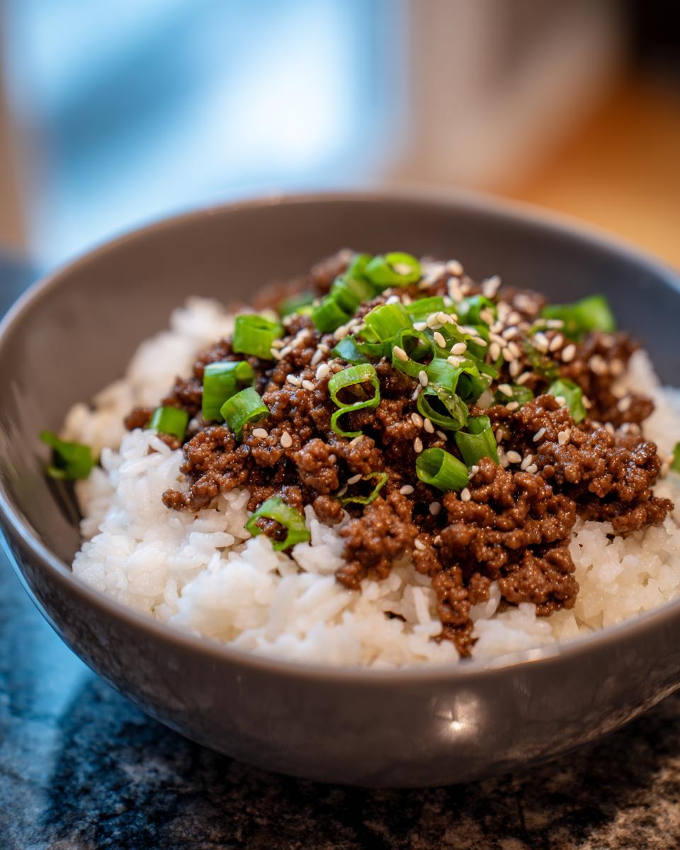 Close-up of a Korean beef rice bowl topped with seasoned ground beef, green onions, and sesame seeds.