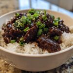 A close-up of a Korean Ground Beef Bowl, featuring tender beef in a savory sauce over fluffy white rice, garnished with green onions and sesame seeds.