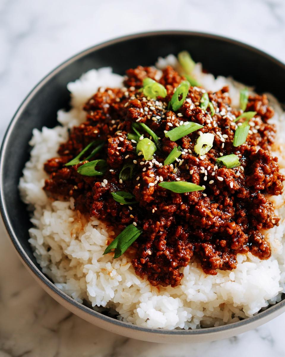A close-up of a Korean Ground Beef Bowl, featuring savory ground beef over fluffy white rice, garnished with sesame seeds and green onions.