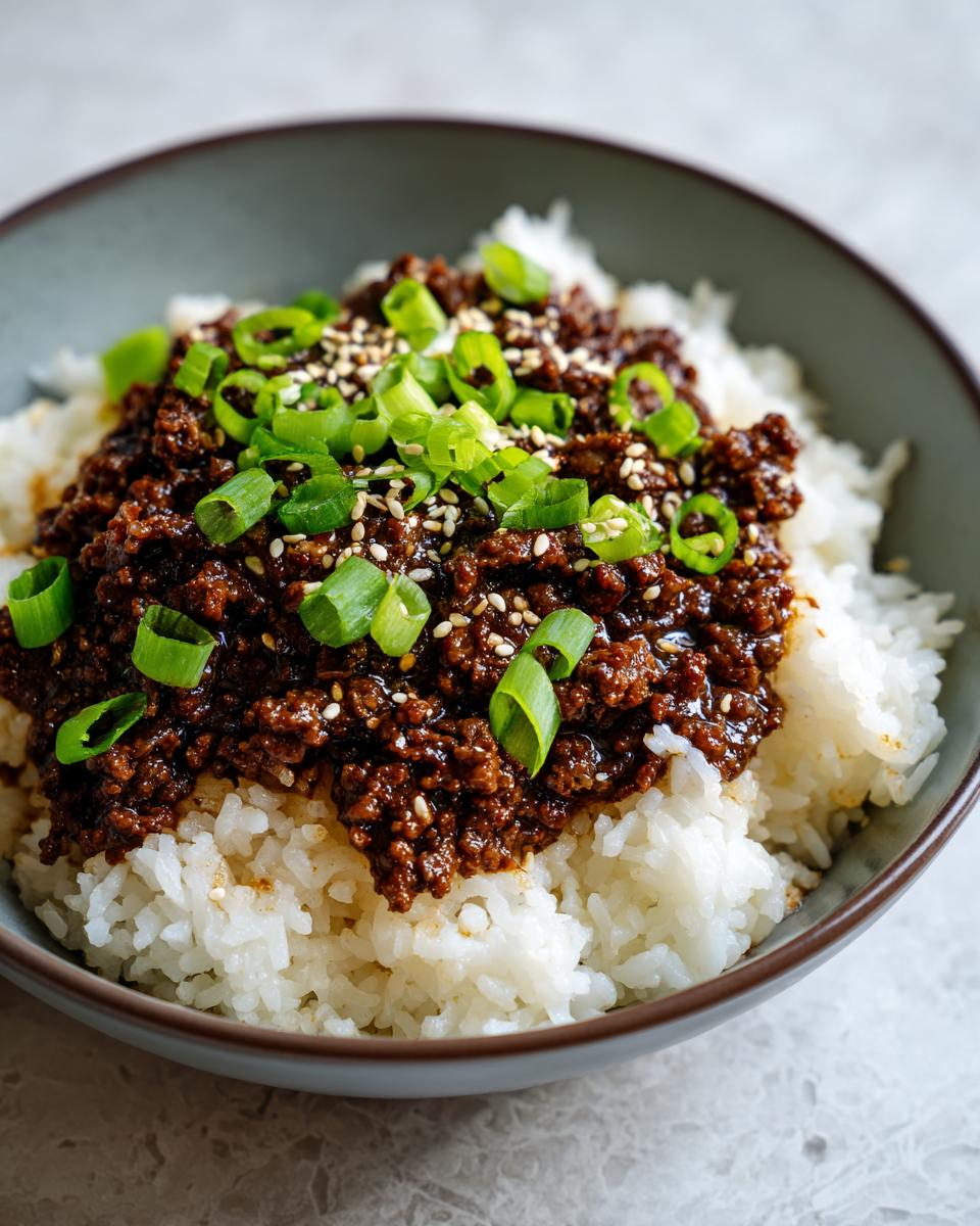 A close-up of a Korean Ground Beef Bowl, featuring savory ground beef over fluffy white rice, topped with green onions and sesame seeds.