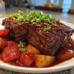 Close-up of a succulent Korean Style Pot Roast served with tender potatoes and carrots in a rich sauce, garnished with green onions and sesame seeds.