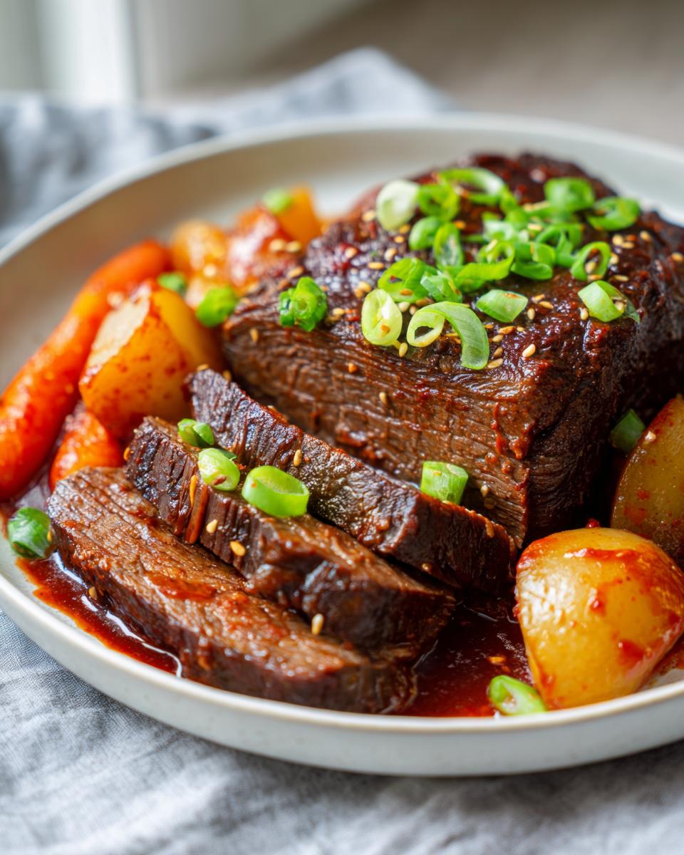 A close-up of a sliced Korean Style Pot Roast served with carrots and potatoes in a rich sauce, garnished with scallions and sesame seeds.