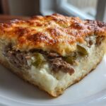 A delicious slice of Low Carb Philly Cheesesteak Casserole on a white plate, featuring melted cheese, steak, and peppers.