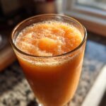Close-up of a tall glass filled with a frosty peach iced tea slush, perfect for hot afternoons.