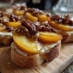 Close-up of crostini topped with creamy brie, sliced peaches, and toasted pecans, showcasing peach recipes with baked brie.