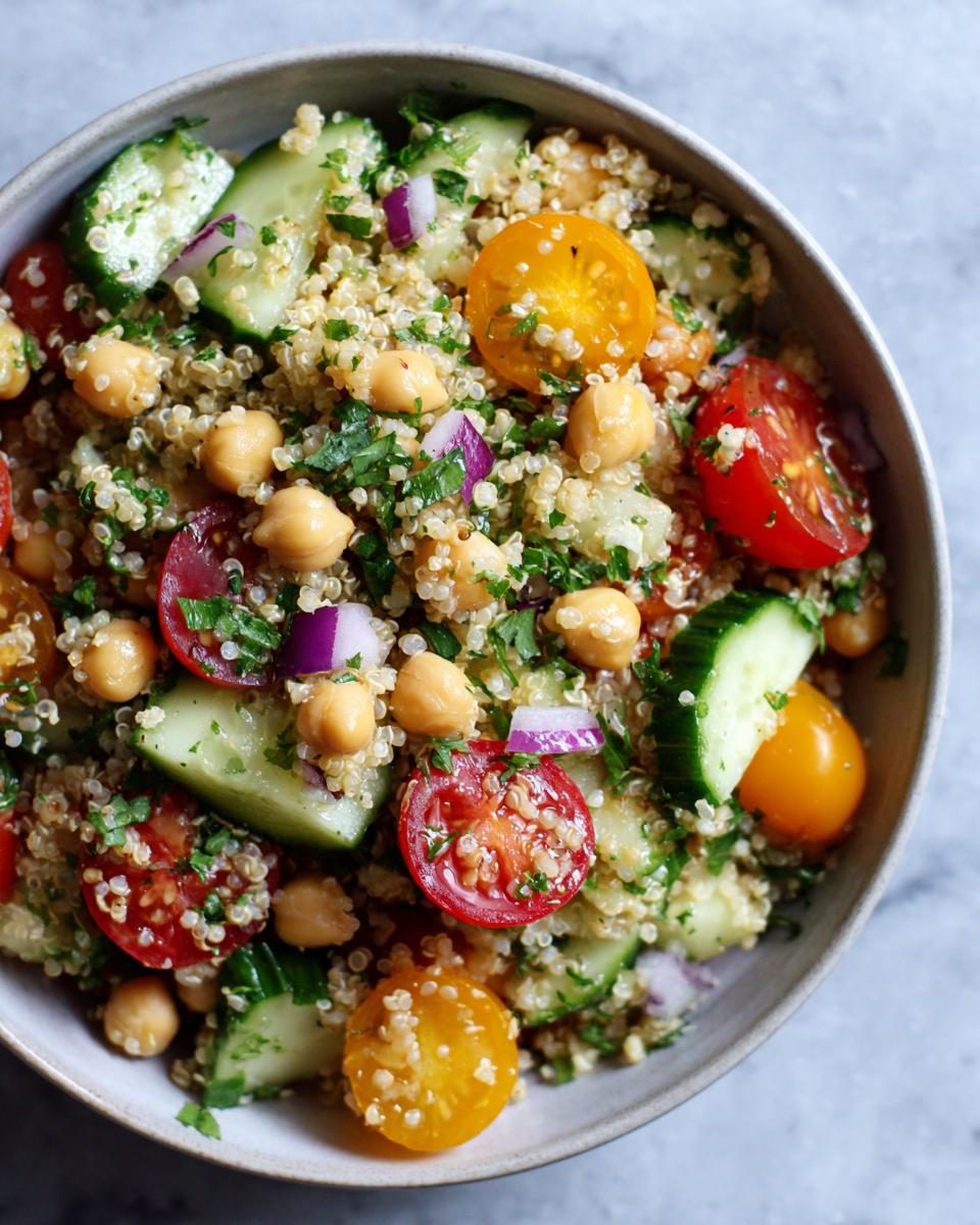 Close-up of a vibrant Quinoa Chickpea Salad with tomatoes, cucumber, red onion, and parsley.
