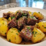 A white bowl filled with tender chunks of Slow Cooker Garlic Butter Beef with Potatoes, garnished with fresh parsley.